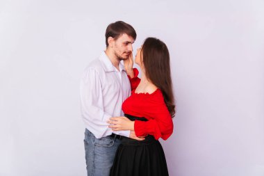 Beyaz bir arka planda sarılan genç bir çift. İzole et. Beyaz gömlekli yakışıklı bir adam, kırmızı köylü kadın bluzu ve siyah korseli uzun İspanyol tarzı saçlı bir kıza sarılıyor. Aşk hikayesi.