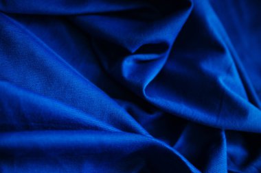 Mavi buruşuk kumaşlı kumaş. Dikiş malzemesi masanın üstünde. Dokuyu kıvrımlarla dikmek