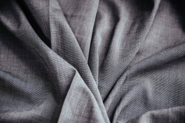 Gri buruşuk kumaş. Dikiş malzemesi masanın üstünde. Katlanmış dikiş dokusu