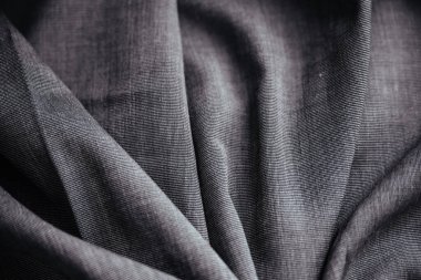 Gri buruşuk kumaş. Dikiş malzemesi masanın üstünde. Katlanmış dikiş dokusu