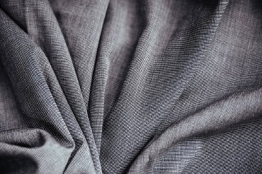 Gri buruşuk kumaş. Dikiş malzemesi masanın üstünde. Katlanmış dikiş dokusu