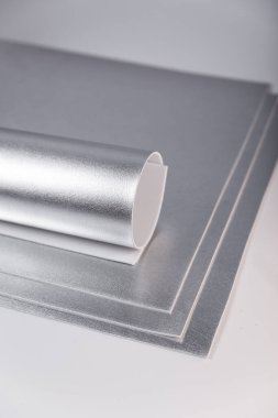 Yuvarlak gümüş karton çarşaf. Parlak isolon çarşaflar. Metalik kağıt. El yapımı materyaller, yuvarlanmış gümüş karton çarşaf. Parlak isolon çarşaflar. Metalik kağıt. El yapımı malzemeler