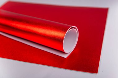 Yuvarlanmış kırmızı karton. Parlak isolon çarşaflar. Izolon. El yapımı malzemeler