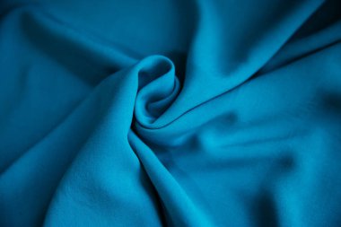 Mavi buruşuk kumaş, masanın üzerinde kumaşlarla birlikte duruyor. Doku.