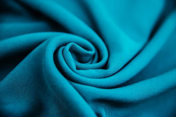 Mavi buruşuk kumaş, masanın üzerinde kıvrımlar ve kumaşlarla yatar.. — Stok fotoğraf