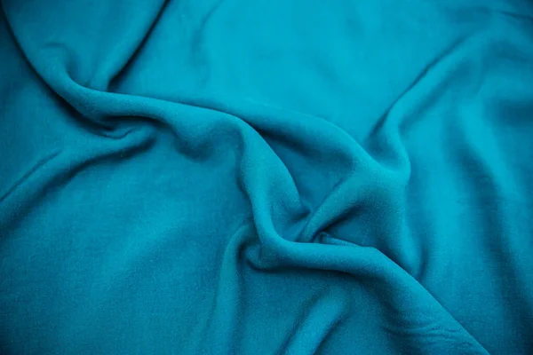 Blue wrinkled fabric lies in folds on the table with drapery. — ストック写真