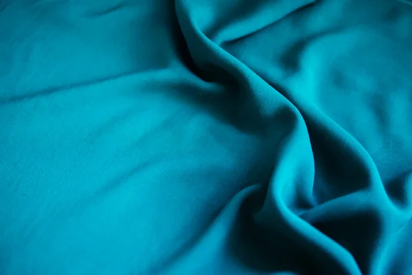 Blue wrinkled fabric lies in folds on the table with drapery. — Stock Photo, Image