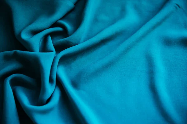 Mavi buruşuk kumaş, masanın üzerinde kıvrımlar ve kumaşlarla yatar.. — Stok fotoğraf