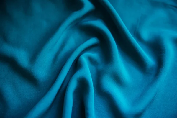 Kék ráncos szövet fekszik redők az asztalon függöny. — Stock Fotó