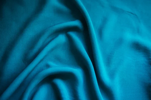 Blue wrinkled fabric lies in folds on the table with drapery. — ストック写真