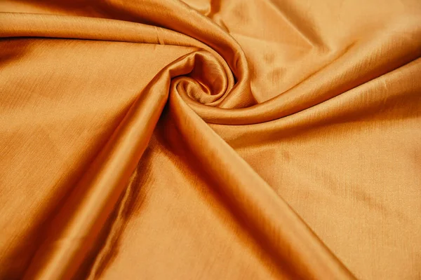 A golden wrinkled fabric lies in folds on a draped table. — 스톡 사진