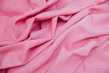 Pembe buruşuk bir kumaş katlanmış bir masanın üzerinde yatıyor. Doku