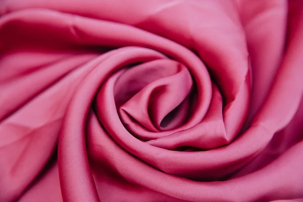 Un tessuto rugoso rosa si trova in pieghe su una tavola drappeggiata. — Foto Stock