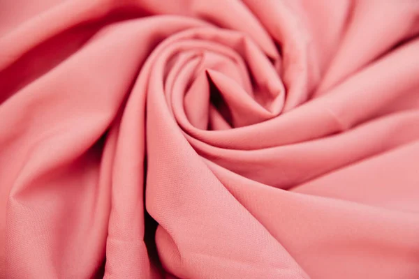 Rózsaszín ráncos szövet fekszik redőkben egy lepedős asztalon.. — Stock Fotó