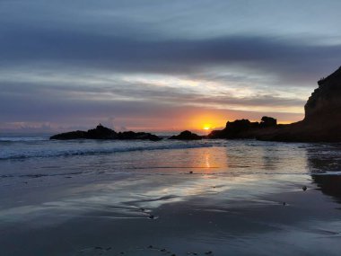 Deniz manzarası, kumsal kayaları ve gün batımında dalgalar. Dalgalar kumsala çarpıyor..