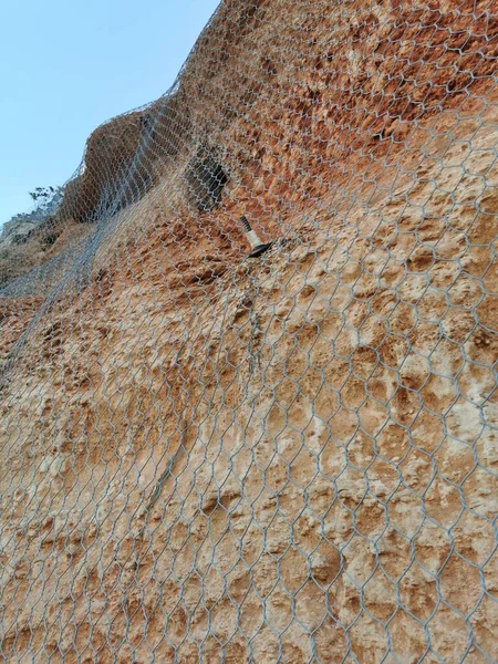 用于防止山体或悬崖滑落岩石的带有网状结构的拱形墙体或固体天然岩石 — 图库照片