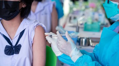 Doktor, Coronavirus veya Covid-19 'u önlemek için üniformalı öğrencilere aşı yapıyor.