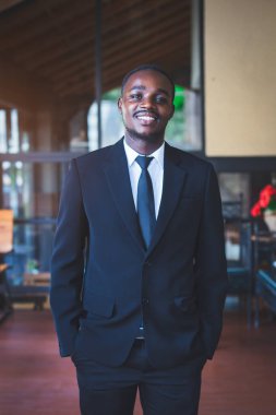 Siyah takım elbiseli zarif Afrikalı işadamının portresi gülümsüyor.