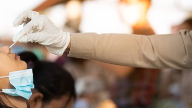 Üniformalı öğretmenler öğrencileri COVID-19 'un okullarda önlenmesi için inceliyorlar. Öğretmen Corona virüsünden pamuklu çubuk kullanan öğrenciler için hızlı antijen test kiti ile örnek aldı