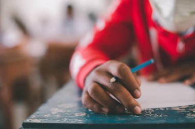 Öğrenci koronavirüs acil durumu nedeniyle yüz maskesi takarken sınava giriyor. Sınıfta oturan genç kadın Covid-19 salgınından dolayı cerrahi maske takıyor.