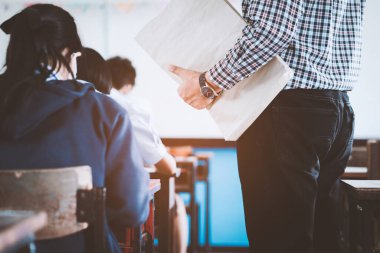 Öğretmen, öğrencilerin sınıfta sınava girmeleri için sınav odasını kontrol ediyor.
