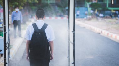 Öğrenciler okullarda Covid-19 'u önlemek için alkol spreylerinin yanından geçiyor