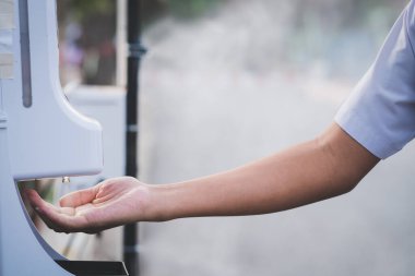 Adamın ellerine otomatik temassız alkol dezenfektanı sıkılmış.