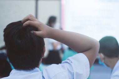 Erkek bir öğrencinin başı ağrıyor çünkü öğretmenin sınıfta ne öğrettiğini anlamıyor. Öğrenci öğrenme sorunları kavramı.