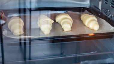 Elektrikli fırındaki çiğ kruvasanlar.
