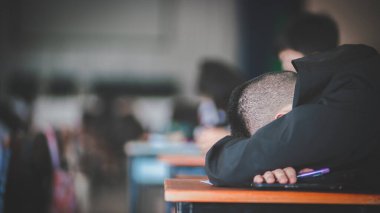 Sınav sınavında uyuyan yorgun üniformalı öğrenciler.