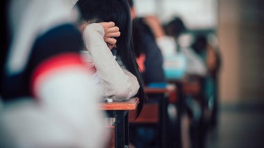 Koronavirüs acil durumu nedeniyle yüz maskesi takan stresli öğrenci sınava giriyor. Sınıfta oturan genç kadın Covid-19 salgınından dolayı cerrahi maske takıyor.