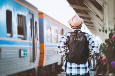 Şapkalı ve sırt çantalı Afrikalı gezgin tren istasyonunda tren bekliyor. Macera yolculuğu konsepti.