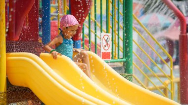 Küçük kız su kaydırağında eğleniyor yaz tatilinde Aqua Park 'ta gülümsüyor ve mutlu.