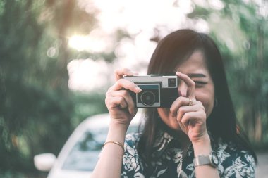 Eski Asyalı turist kız mutlu bir şekilde doğayı ve manzaraları fotoğraflıyor. Araba konseptiyle macera seyahati.