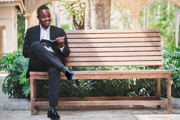 Knappe Afrikaanse Zakenman Een Pak Zit Blij Een Boek Lezen — Stockfoto