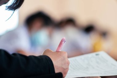 Koronavirüs acil durumu nedeniyle yüz maskesi takan öğrenci sınavına giriyor. Sınıfta oturan genç kadın Covid-19 salgınından dolayı cerrahi maske takıyor.