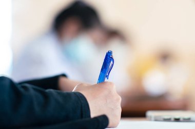 Koronavirüs acil durumu nedeniyle yüz maskesi takan öğrenci sınavına giriyor. Sınıfta oturan genç kadın Covid-19 salgınından dolayı cerrahi maske takıyor.