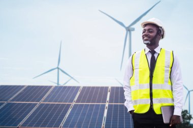 Afrikalı mühendis elinde tablet bulunan güneş fotovoltaik ve rüzgar türbinleri elektrik santrali üretiyor..