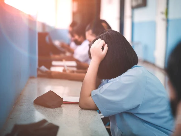 Students taking exam with headache and stress