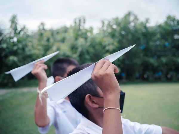 Asian students playing paper rocket in the park of school