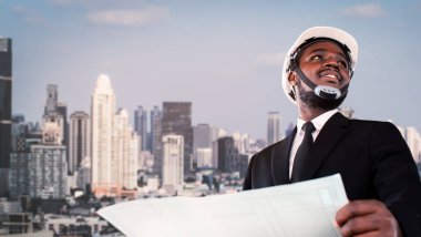 Beyaz kask takan Afrikalı mimar mühendis arka planda modern bir binada duruyor. Mühendislik konsepti ve kentsel yapı