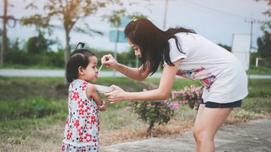 Mother feeding her daughter with a spoon. Mother giving food to her little girl child