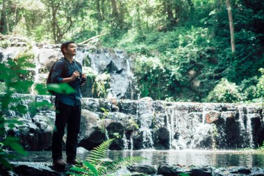 Hiking tourists with binoculars stand at the waterfall.Expedition concept, Traveling Concept. Hiker concept.