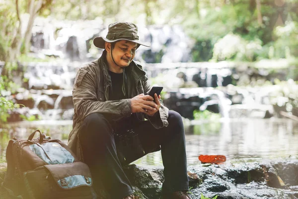 Viajero Masculino Sonríe Mientras Mira Teléfono Inteligente Con Mochila Costado —  Fotos de Stock