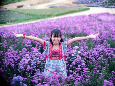 Margaret çiçeklerinin olduğu bir tarlada yerli gibi gülümseyen bir kız.