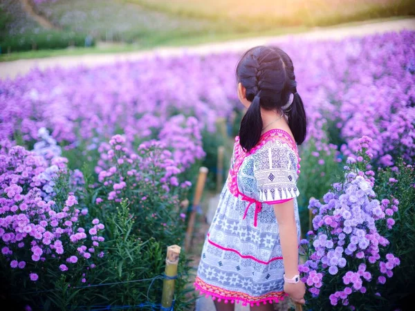 Asian little girl in native dress stands in a field of margarets flowers