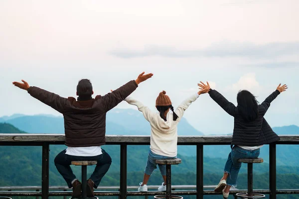 Happy family, featuring father, mother and daughter, raising their arms to convey Freedom with a view of the mountains in the background