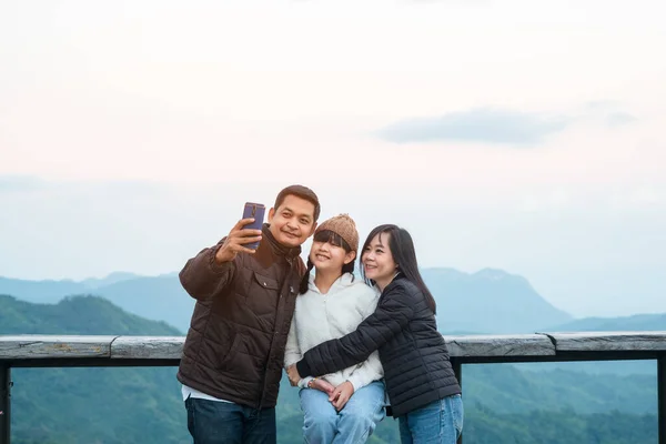 Happy family holding smart phone selfie photo with beautiful mountain landscape nature background