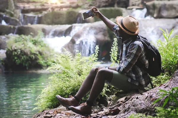 アフリカの男性旅行者は 休暇中に写真を撮り スマートフォンを使うことを喜んでいます アドベンチャーツーリズムとテクノロジーの概念 — ストック写真