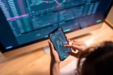Yakın plan - Kadın akıllı telefon, kripto para birimi gelecekteki fiyat öngörüsünde Bitcoin fiyat tablosunu kontrol ediyor.